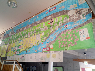 校舎内の階段に大きく張り出されている、前年度の4年生たちがまとめの作業で作った「わたしたちの多摩川」マップ。