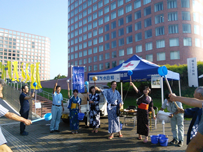 7月20日に東京都からの呼びかけで実施した、打ち水イベント「福生打ち水日和」。水は都下水道局の再生水を活用し、ひしゃくやのぼり旗、はっぴなども都からの提供があった。当日は、職員も浴衣を着て、市長とともに一斉に打ち水をした。「ふっさ環境市民会議」のメンバーも知り合いに声をかけて集まり、打ち水を盛り上げに一役買った。