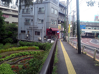 すぐ脇には片道3車線の大通りが走り、正面にはJR京浜東北線の高架が間近に見える。飲食店が立ち並ぶ手前から開けた緑地が見下ろせる場所があり、眼下に色鮮やかな花壇が広がる。