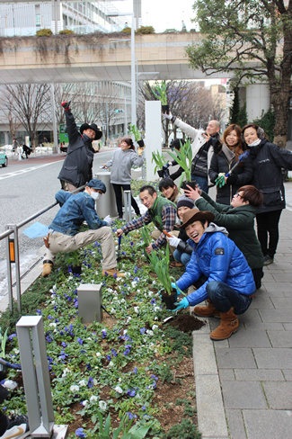 六本木けやき坂通りの花壇にチューリップの球根苗を植えるGREEN UPの参加者たち。