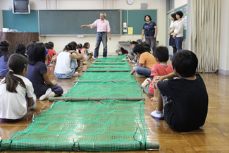 井荻小学校・特活室の教室で、ヤゴフロート製作の説明をする境原さん