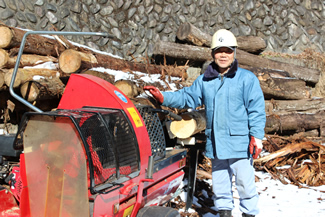 フィンランド製の自動薪割り機と講師の大谷正平さん。便利な機械だが、扱いは繊細だ。5.7トンの力で薪を割っていく