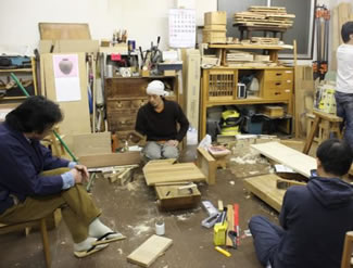 木工駆け込み塾の工房。床に座ってカンナをかける塾生たち。電動工具もまれに使うことはあるが、手道具による木工作業がメインだからこそ、住宅街の中でも仕事ができる。