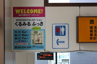 福生駅西口の階段の壁に張り出されたサイクルシェアリングの表示「行って Go！　乗って Ride！　楽しむ Fun！」。