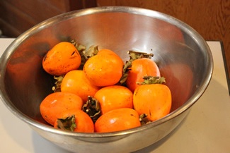 ボウルに10個ずつ取り分けられた柿の実（1人分）。包丁で皮を剥いて、紐に吊るして干し柿にする。