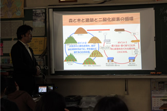 森と木と建築と二酸化炭素の循環について図で説明する大坂さん。中野先生によるこれまでの授業のふりかえりを受けて、大坂さんがまとめの解説をする。