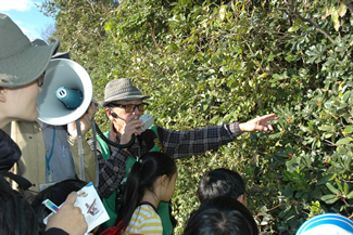 植物を手に解説するNPO法人 東京港グリーンボランティア理事の田中良平さん。