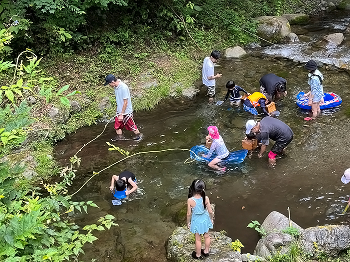 川に入ってしばらくすると全員が川の流れに慣れ、用意されていた水中眼鏡や水鉄砲、浮き輪などを使って川遊びを楽しみました。